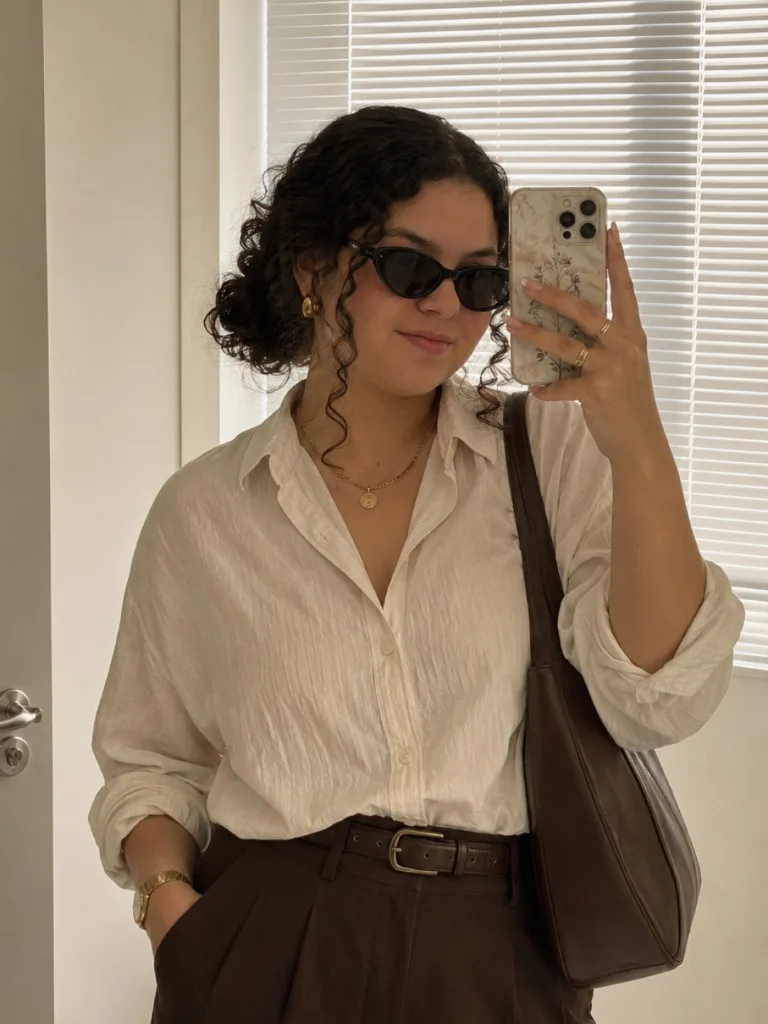 Ensaio gerado com IA: selfie no espelho, camisa branca e calça marrom.
